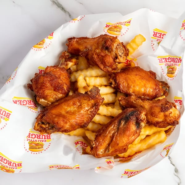 Cali Style Burger's golden-brown fried chicken wings and crinkle-cut fries in branded paper.
