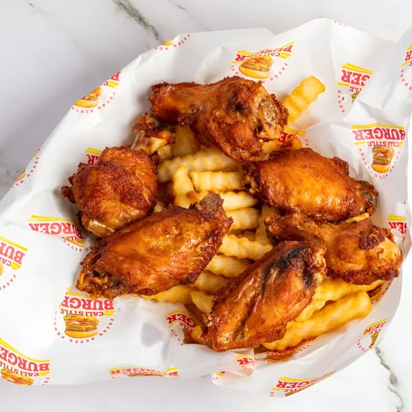 Golden-brown fried chicken wings and crinkle-cut fries in Cali Style Burger branded paper.